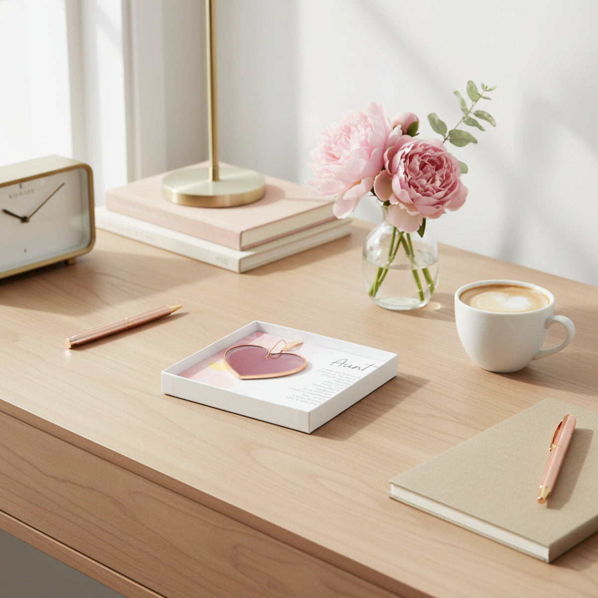Pink rose mauve glass heart with Aunt sentiment in white box with clear lid laying on a woman's desk.