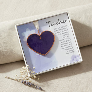 3 of 5:Textured stained glass purple heart with Teacher sentiment in a white box with a clear lid displayed on a throw.
