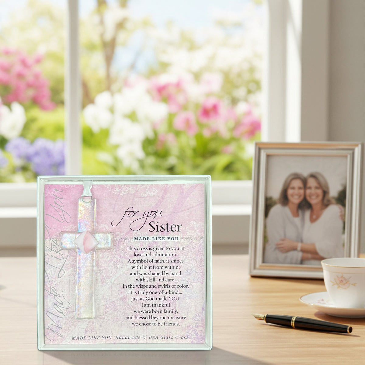 "For You, Sister" cross gift on a desk with a photo of two sisters.