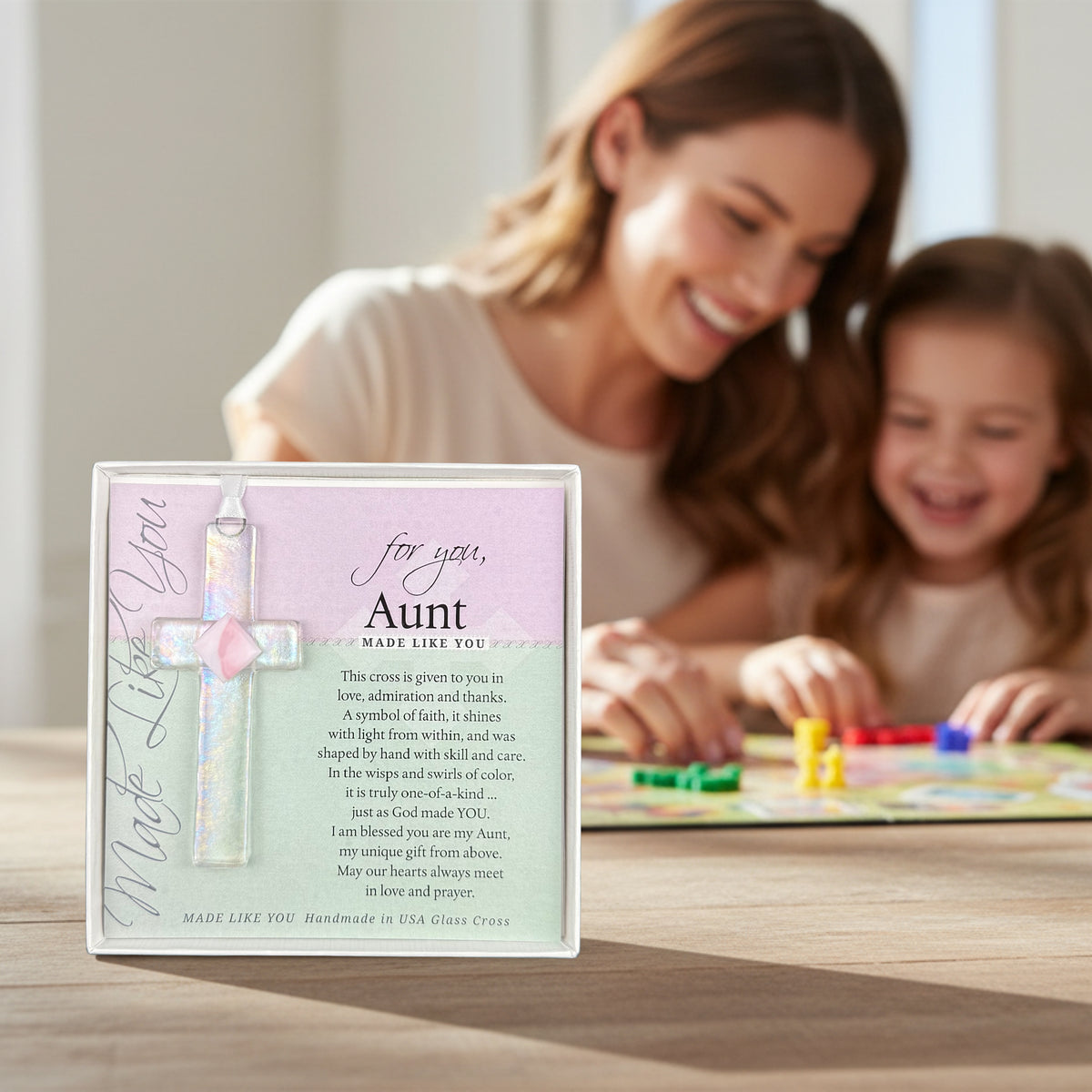 "For You Aunt" cross on a table with an aunt and her niece playing a game in the background.