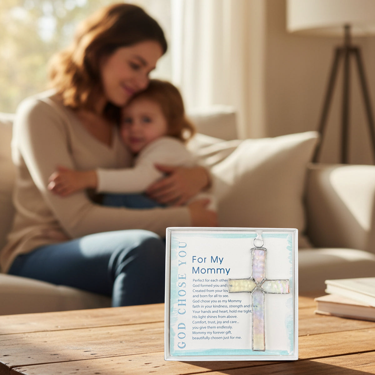 "For My Mommy" cross gift on a table with a mother and child snuggling in the background.