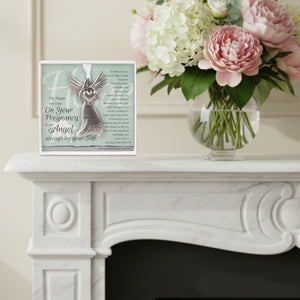 2 of 4:Pregnancy gift sitting on a mantle next to a vase of flowers.