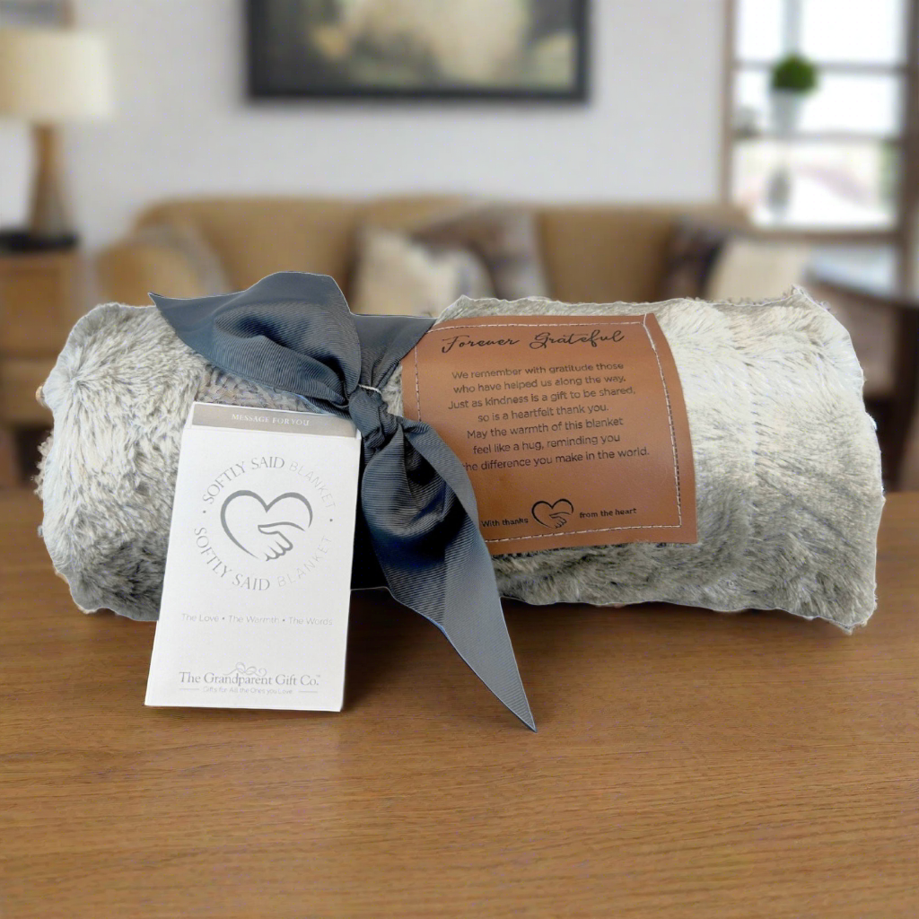 Forever Grateful blanket rolled and tied with a gray grosgrain ribbon.