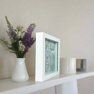 4 of 6:Framed Baptism cross on a bookshelf.