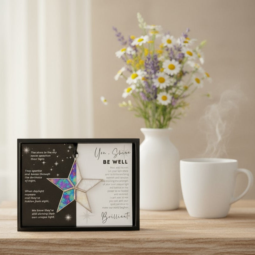 Handmade 4" clear iridescent stained glass star with silver edging, packaged with "You + Shines Be Well" sentiment in black gift box with clear lid.
