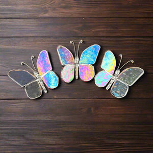 4 of 5:Three iridescent stained-glass butterflies on a wooden table.