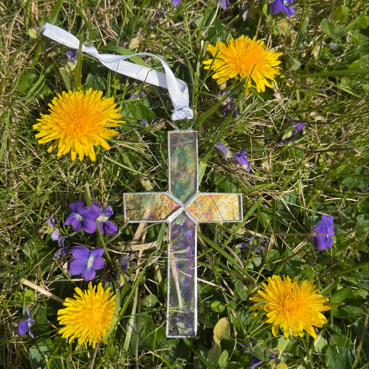 Clear iridescent stained glass cross with white satin ribbon for hanging.