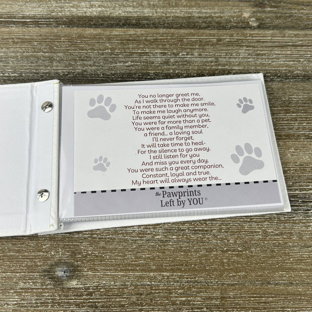 Photo album laying open on a table showing "The Pawprints Left by You" poem.