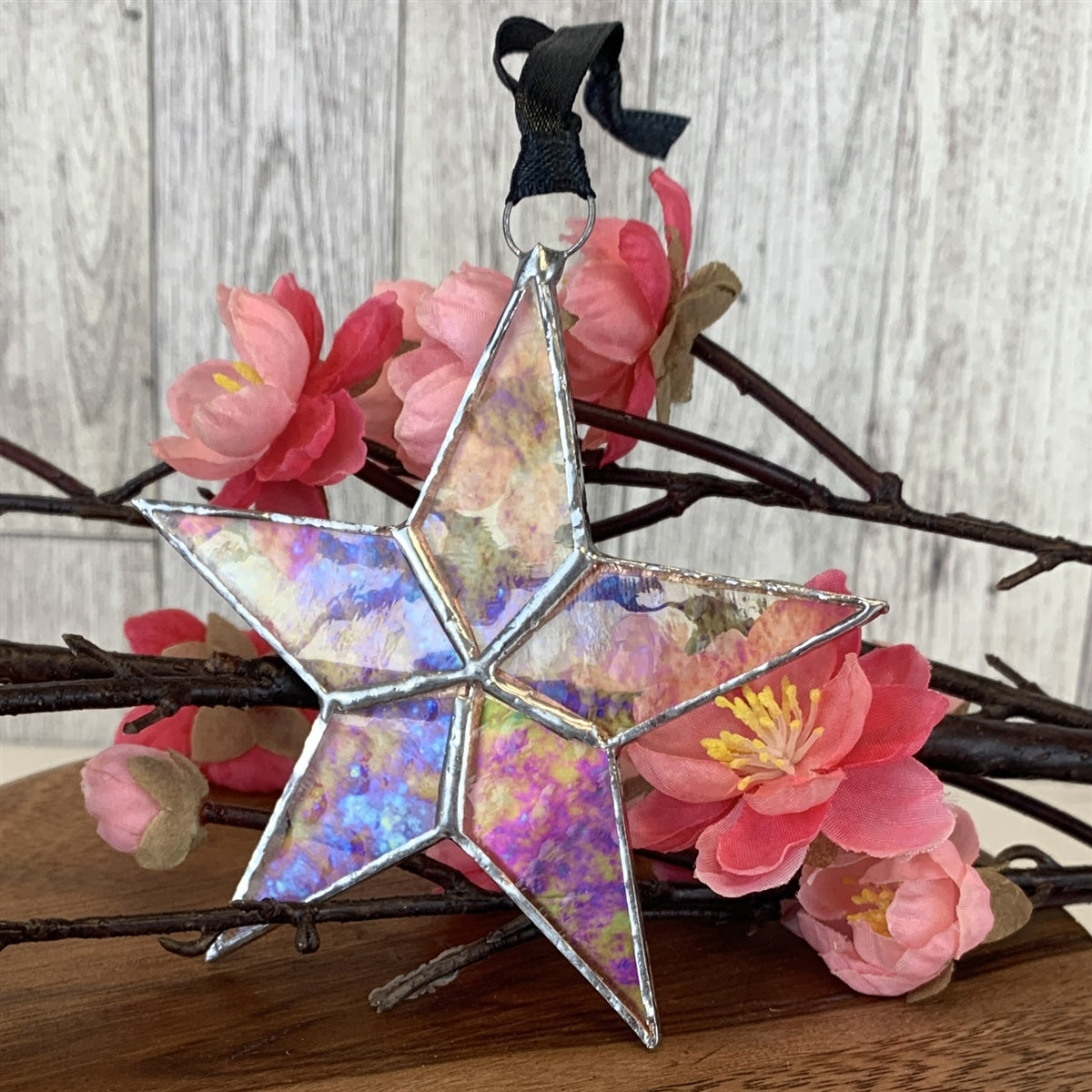 Clear iridescent stained glass star with silver edging with black satin ribbon.