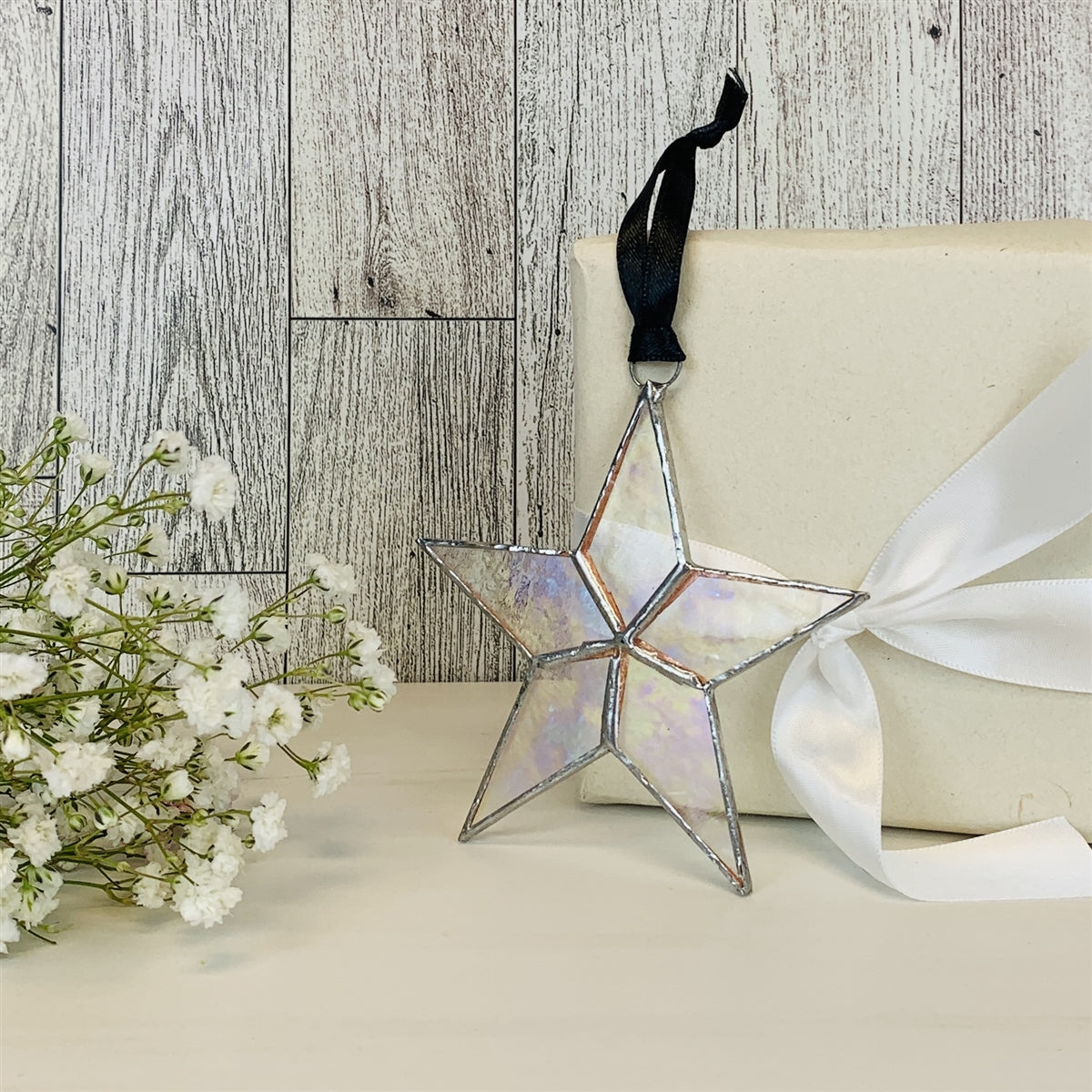 Clear iridescent star with black satin ribbon for hanging.