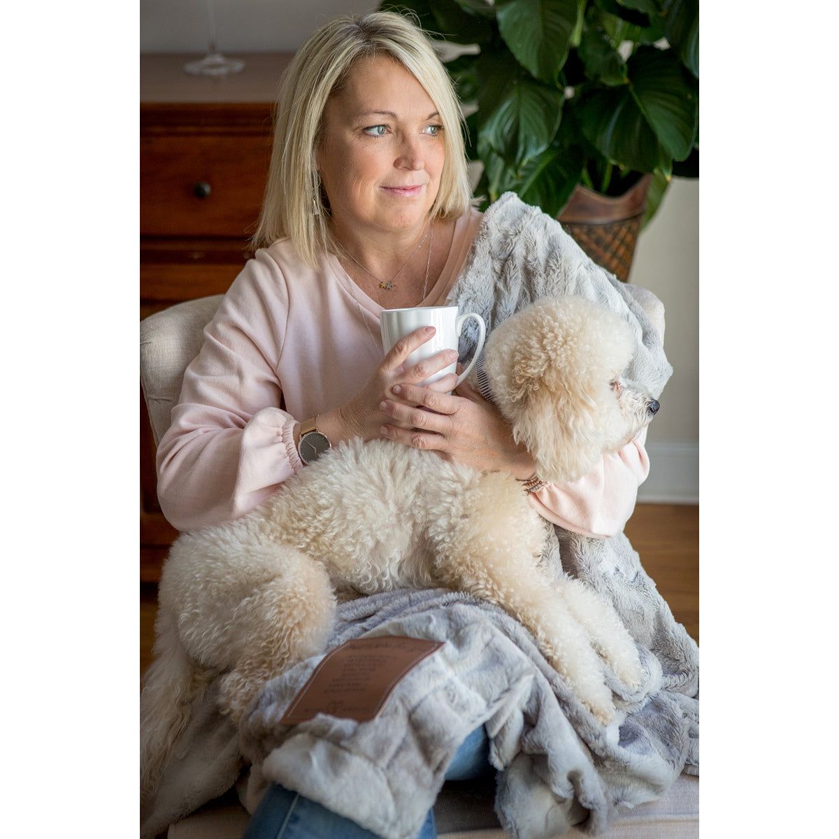 A woman and her dog snuggling with the Praying for You blanket.