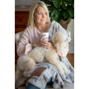 5 of 8:A woman and her dog snuggling with the Praying for You blanket.