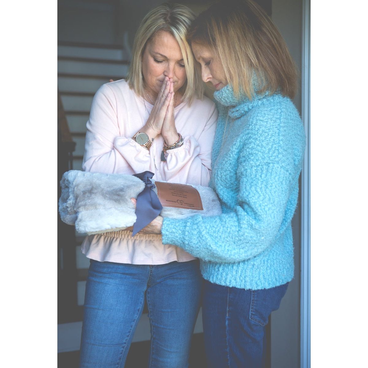 Two women exchanging the Praying for You blanket.