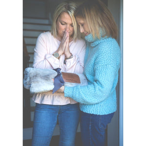 6 of 8:Two women exchanging the Praying for You blanket.