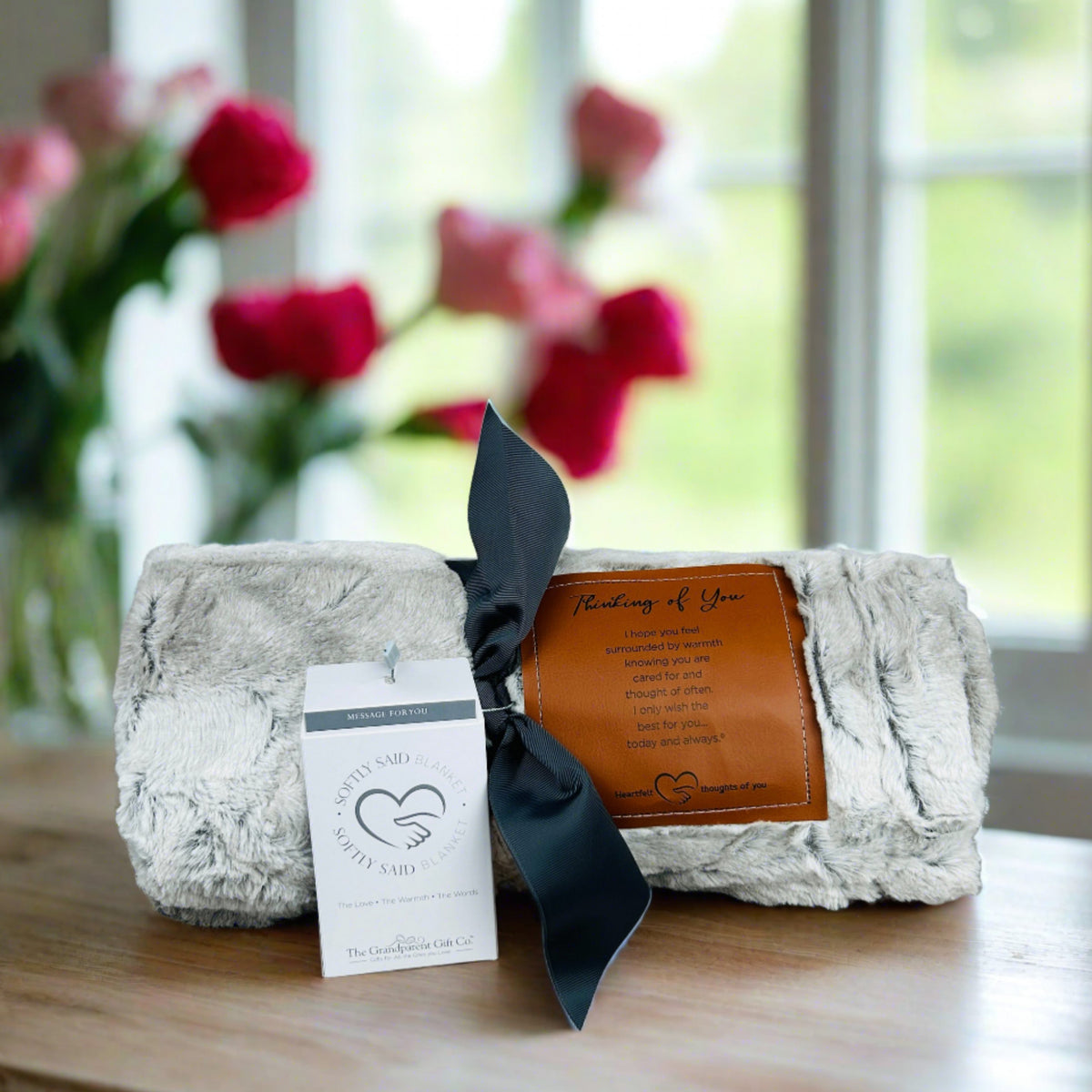 Thinking of You blanket rolled and tied with a gray grosgrain ribbon.