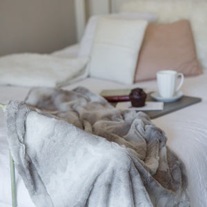 5 of 11:Blanket draped over the end of a bed. Gray variations and soft texture are shown.