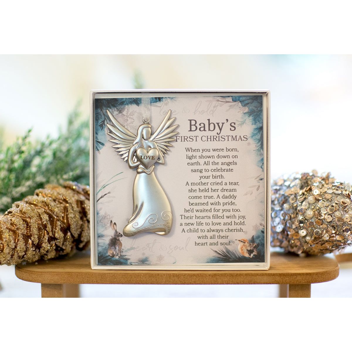 Baby's First Christmas angel ornament in box in a Christmas setting.