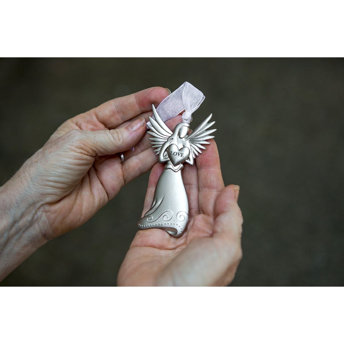 Silver toned angel holding a heart with the word &quot;LOVE&quot; engraved. Angel has white organza ribbon for hanging.