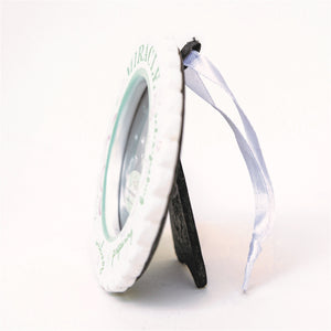 5 of 5:Side view of Miracle ornament with easel back for tables and white satin ribbon for hanging.