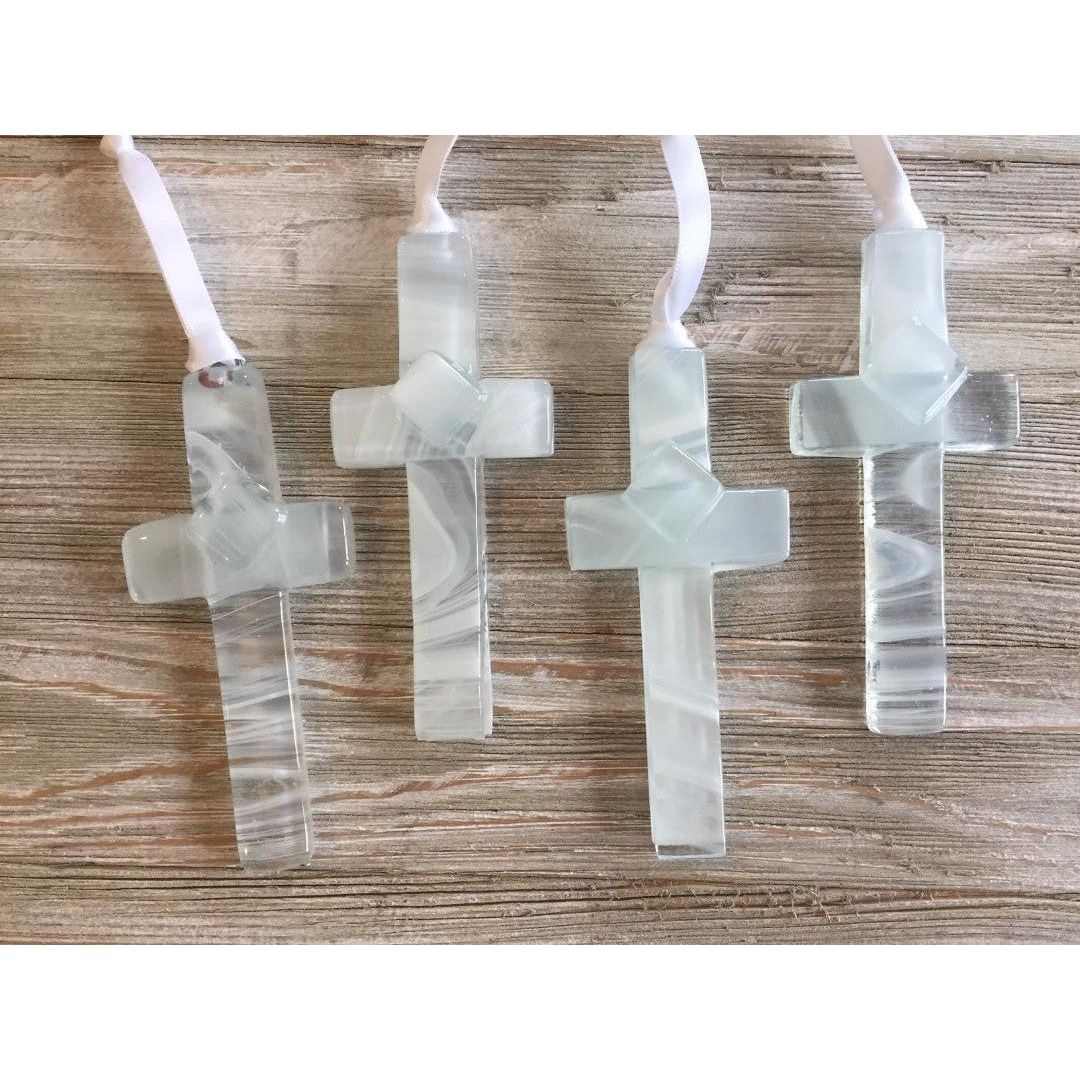 An assortment of clear glass crosses with white swirls.