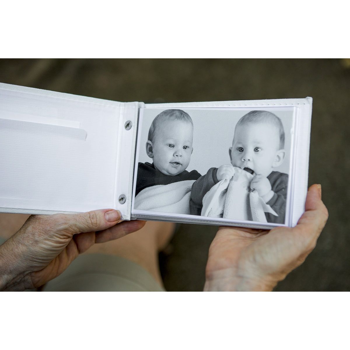 Grand Twins brag book being held open showing the photo pockets and inside of the front cover.