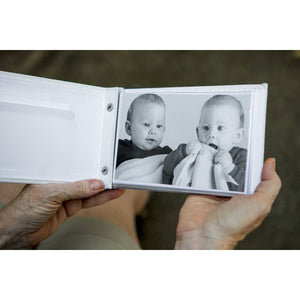 3 of 6:Grand Twins brag book being held open showing the photo pockets and inside of the front cover.