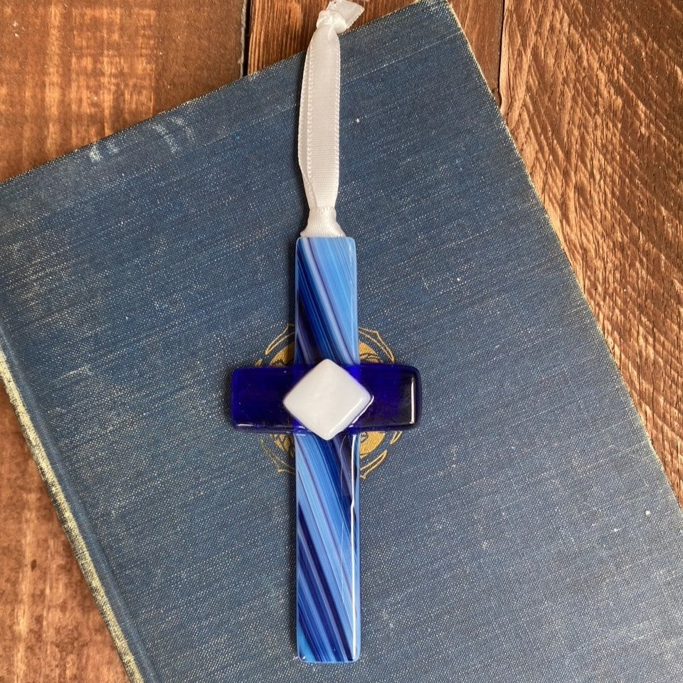 4" blue glass cross sitting on a book.
