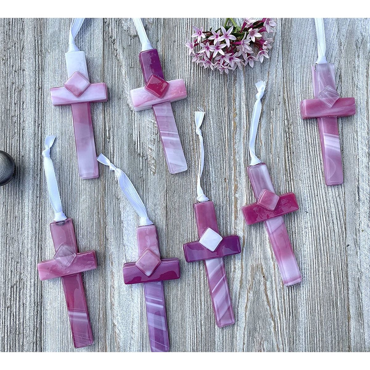 An assortment of pink glass crosses, each one is unique.