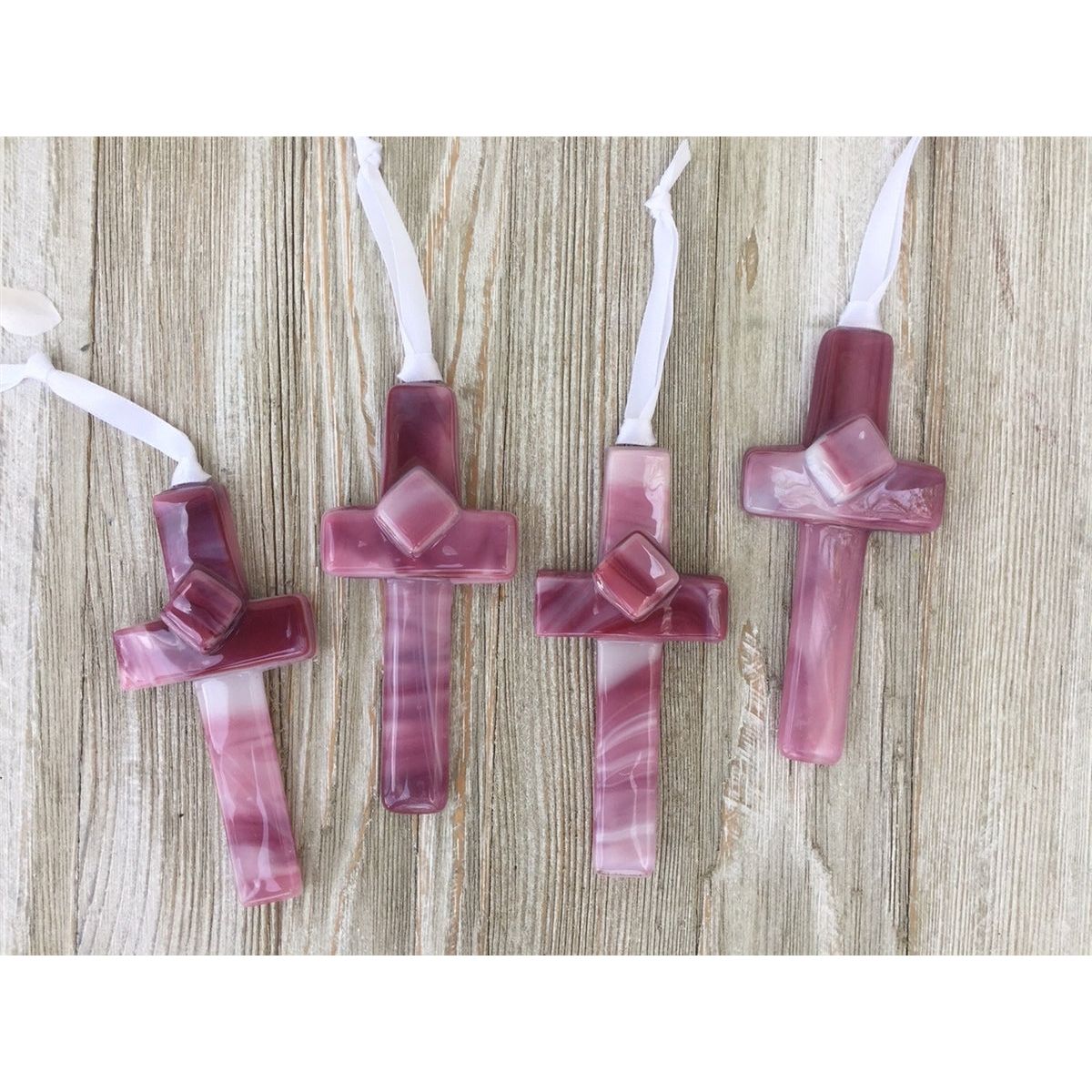 Assortment of pink glass crosses with variations of white to dark pink.