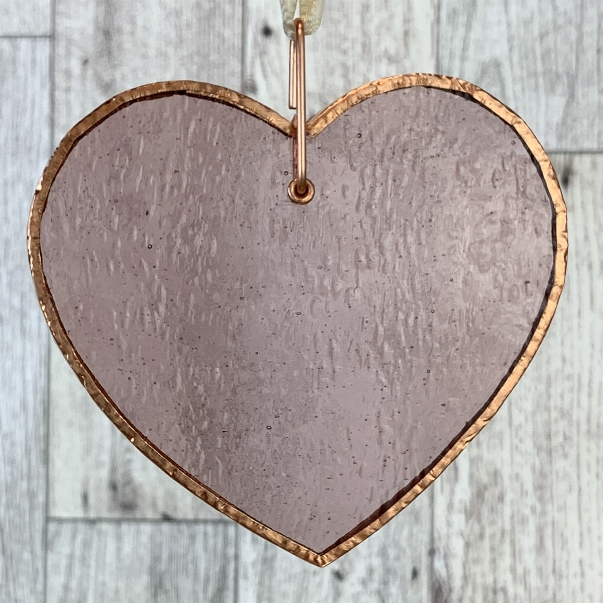 Translucent rose-mauve heart with copper edging and off-white satin ribbon for hanging.