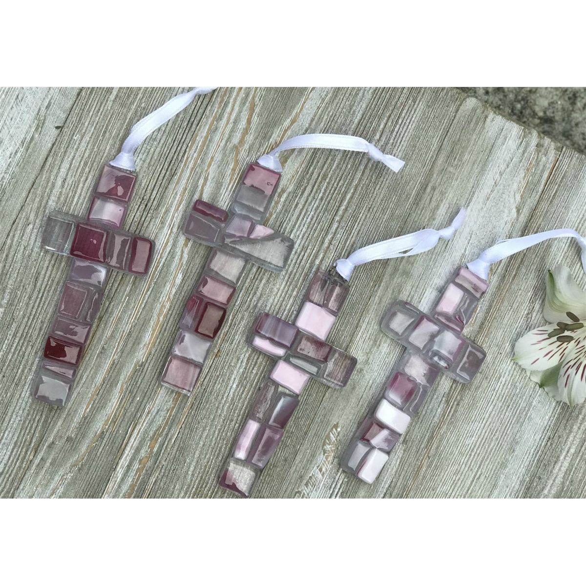 An assortment of pink mosaic crosses, each one is unique.