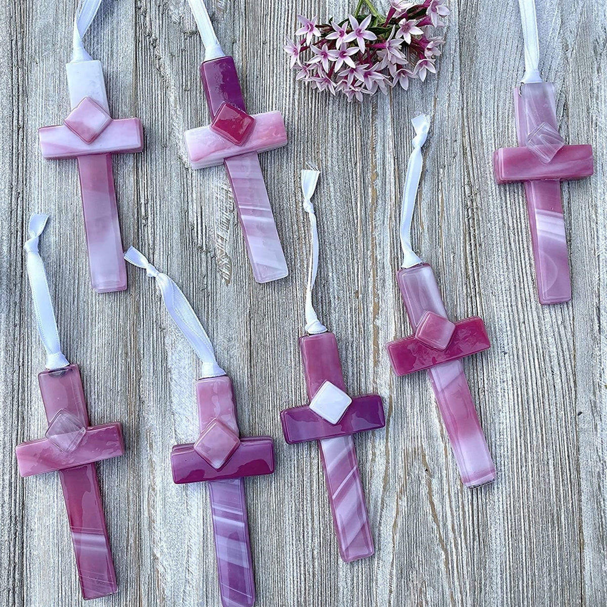 An assortment of pink glass crosses, each one is unique.