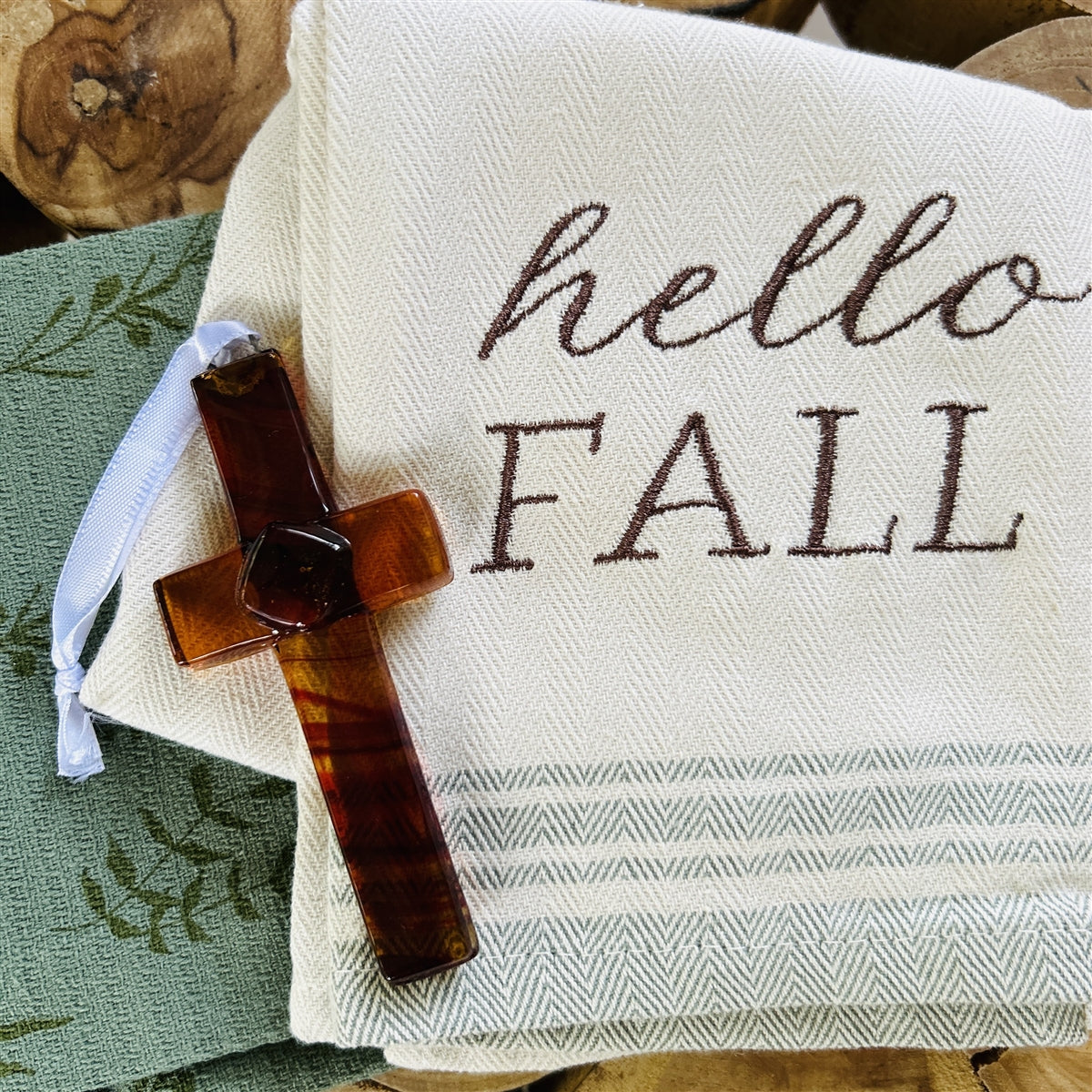 Amber/brown glass cross with white satin ribbon for hanging.