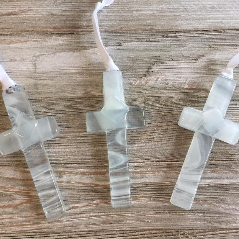 An assortment of clear glass crosses with white swirls.