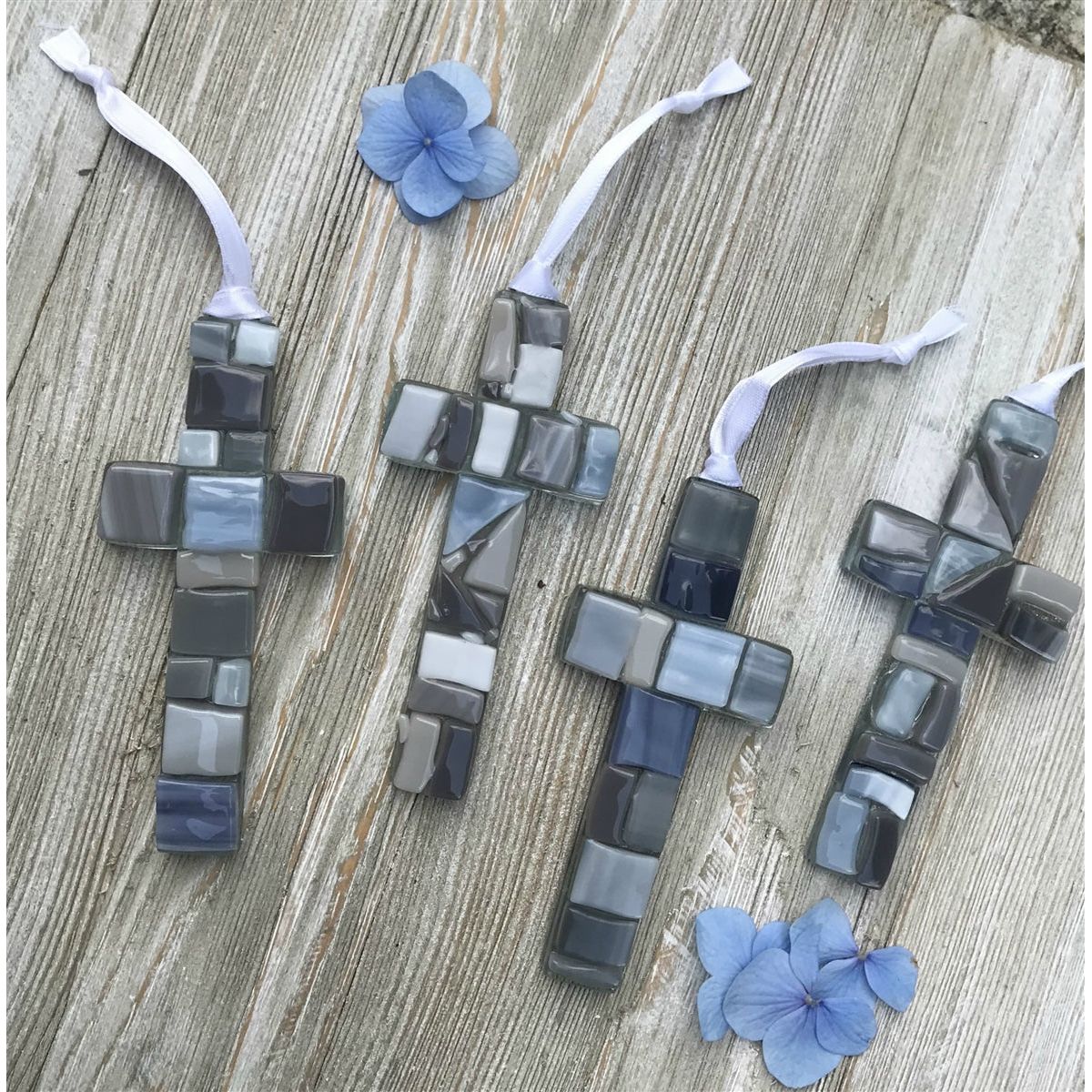 An assortment of gray mosaic crosses, each cross is unique.