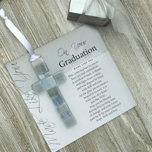 2 of 4:Gray mosaic cross with shades of gray, white, or blue lying on the