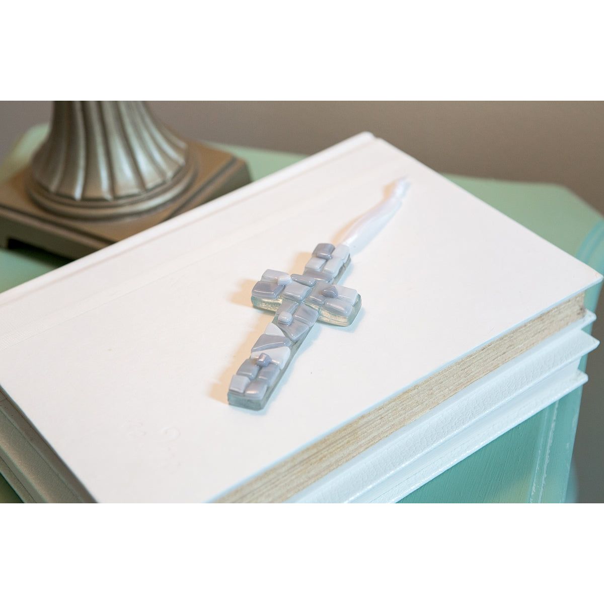 Gray mosaic glass cross with white satin ribbon for hanging.