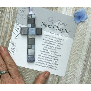 4 of 4:Gray mosaic cross with shades of gray, white, or blue lying on the