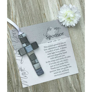 2 of 3:Gray mosaic cross with shades of gray, white, or blue lying on the