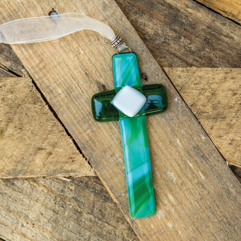 4" glass cross made with green glass in shades of green and blue. Includes an organza ribbon with pewter accent bead for hanging.