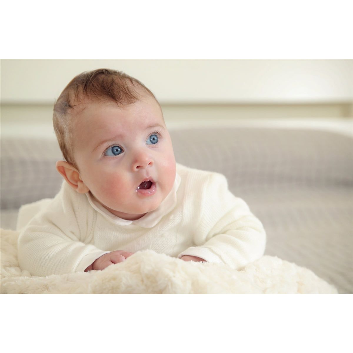 Blue eyed baby with a white outfit on.