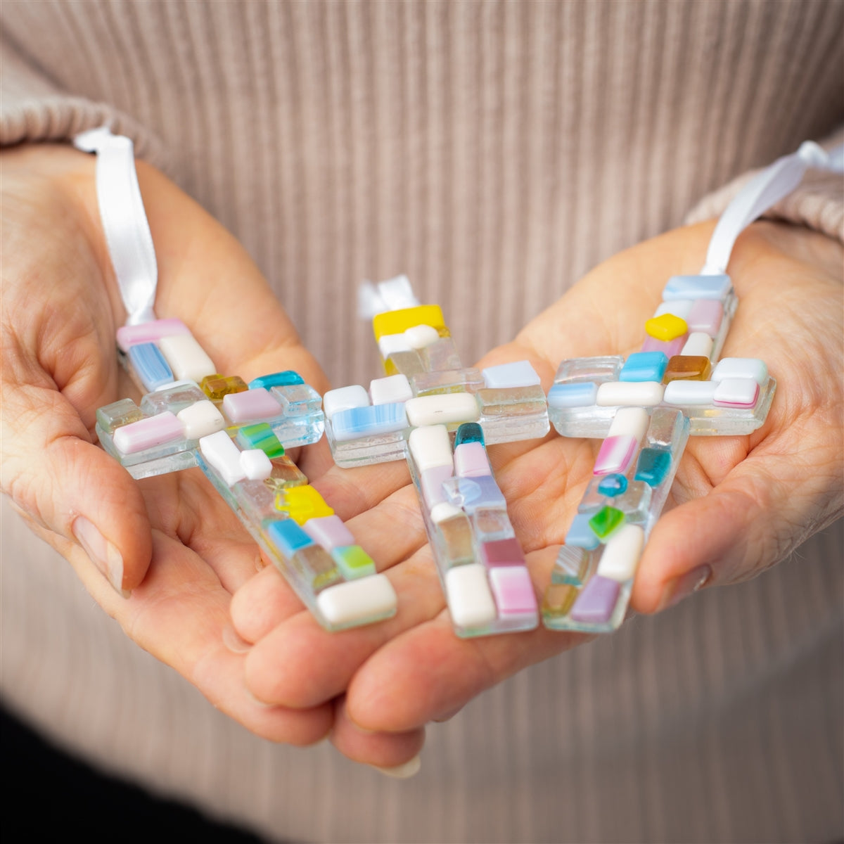 An assortment of pastel mosaic crosses with varying shades of pastel glass.