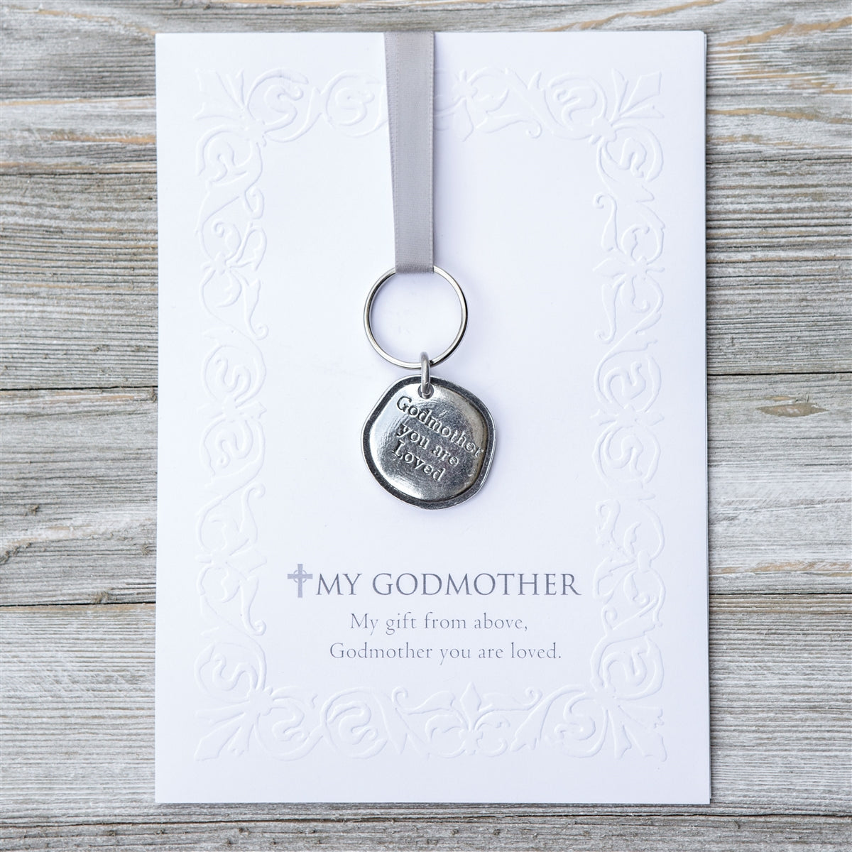Keychain with pewter coin that says "Godmother you are loved" packaged with an embossed notecard with My Godmother sentiment.