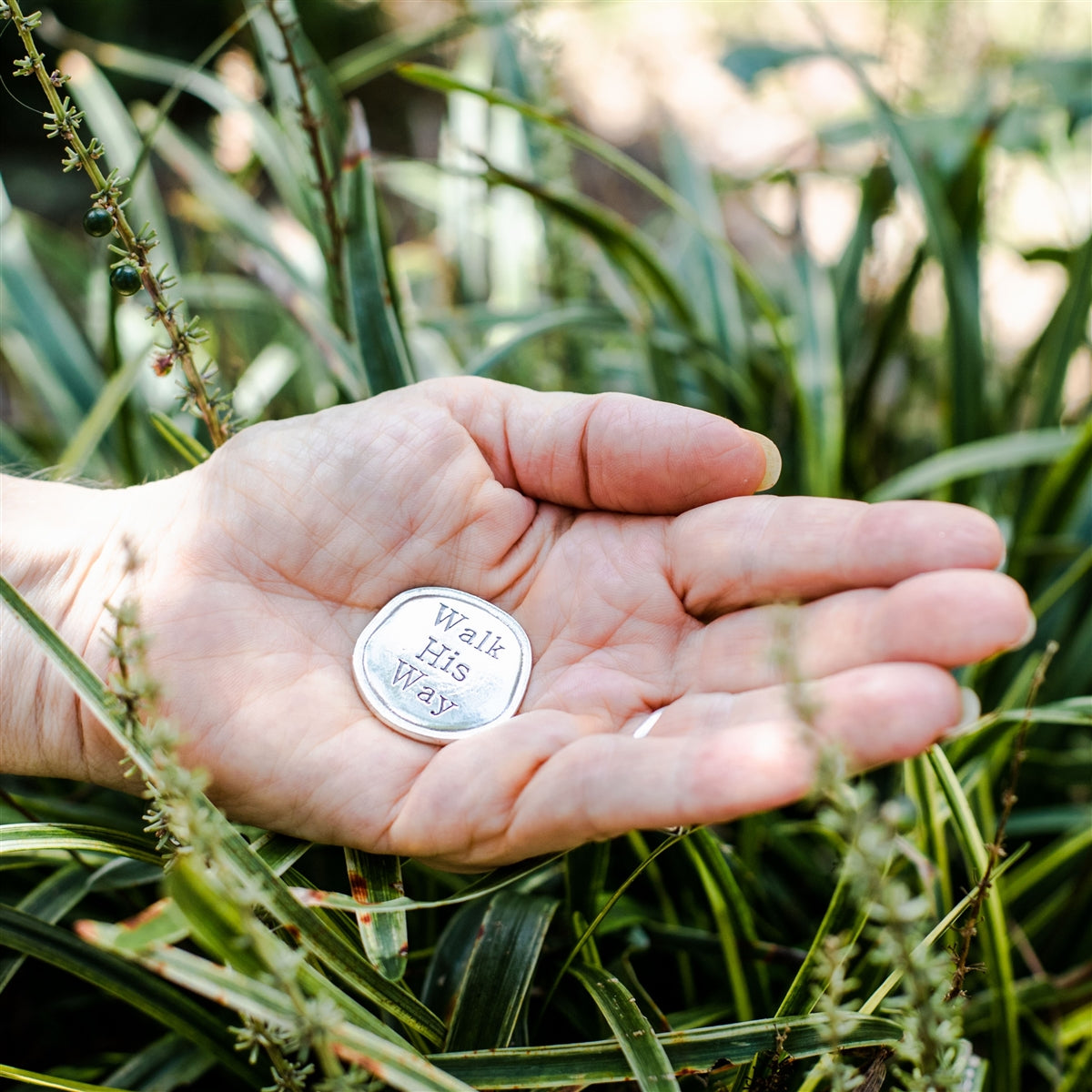 Pewter coin being held in hand.