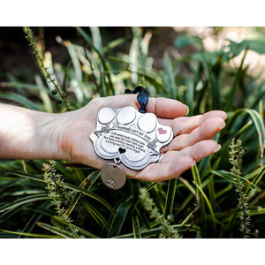 5 of 6:Pawprints Left By You pet tag ornament being held in a hand.