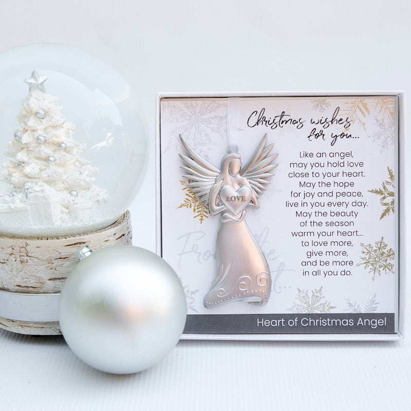 Christmas Wishes Angel in a Christmas setting. Angel is holding a heart with the word "LOVE" and has a white organza ribbon for hanging.