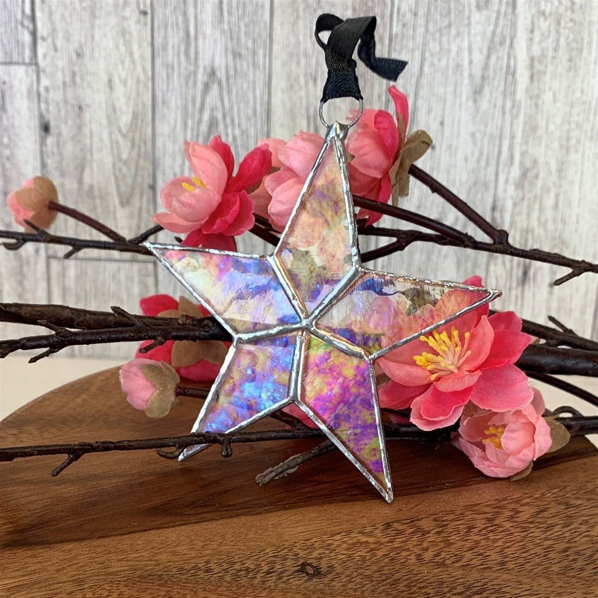 Clear iridescent stained glass star with silver edging with black satin ribbon.
