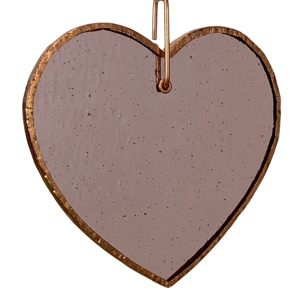 Pink glass heart with bubbles, ripples and texture inherent to handmade glass.