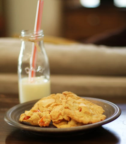 A plate of orange slice cookies and a glass of milk.