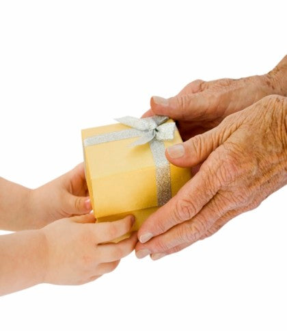 Grandchild and Grandparent's hands exchanging a gift.